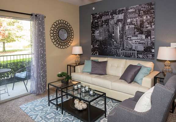 A living room with a couch, chair, and a large picture on the wall. at Infinity on Sunnyvale Apartments , Mesquite, 75150