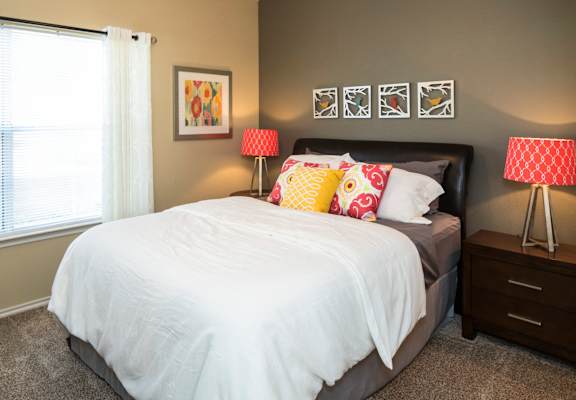 A bedroom with a white bed and two red and white lamps. at Infinity on Sunnyvale Apartments , Mesquite, 75150