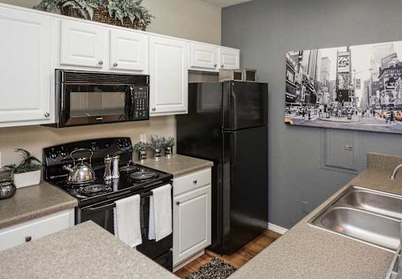 A black refrigerator sits in a kitchen with white cabinets. at Infinity on Sunnyvale Apartments , Mesquite, 75150