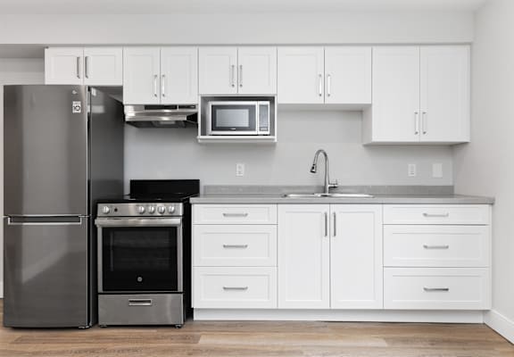 A modern kitchen with a stainless steel refrigerator, oven, and microwave.