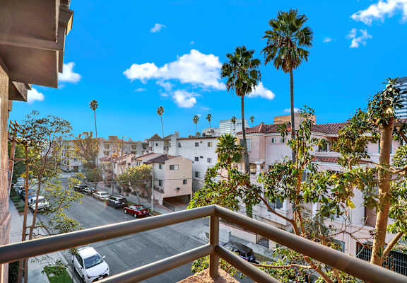 A balcony view of a residential area with palm trees at Twelve One Ten Rochester, Los Angeles