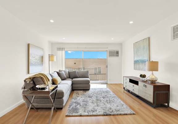 A modern living room with a grey sofa and a wooden floor at Wooster Encore Apartments, CA 90035