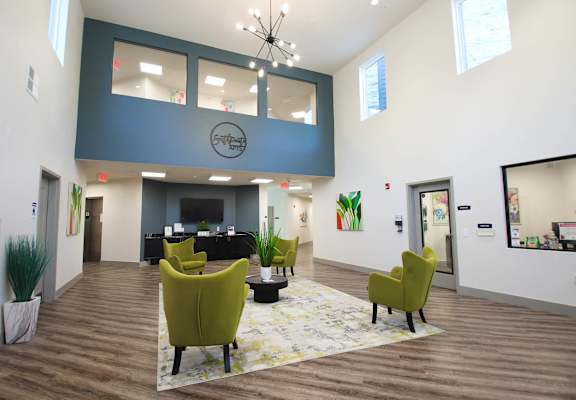 a large lobby with yellow chairs and a blue accent wall at SouthPointe Village Apartments, LP, Fishers, Indiana