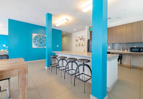 A kitchen with a bar area and a clock on the wall.