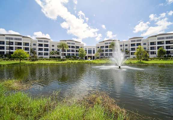 a pond with a fountain in front of an apartment building
