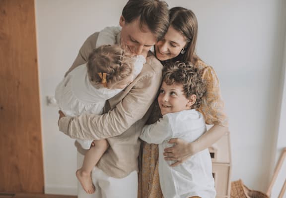a man and woman holding two children and a baby in a room