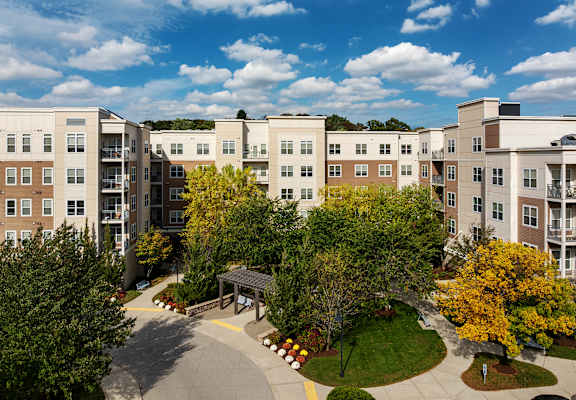 A view of apartment buildings with a walkway and trees in the foreground.