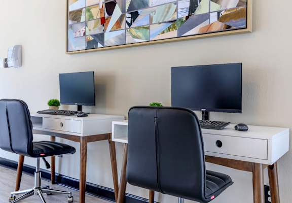 two desks with two monitors and two chairs in a room at The Davis Apartments, Huntsville, 35816