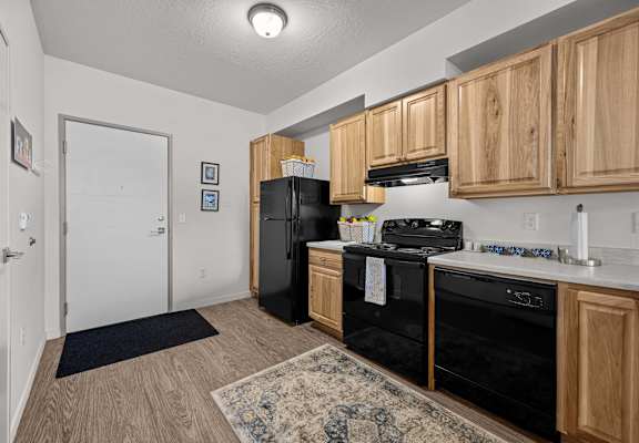 A kitchen with black appliances and wooden cabinets.