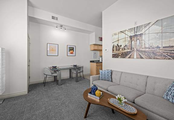 A living room with a grey couch, a coffee table, and a painting of a bridge on the wall.