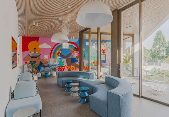 a lobby with blue couches and chairs and a colorful mural