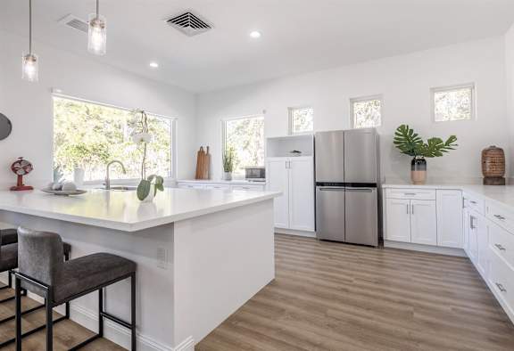 a large white kitchen with white cabinets and a stainless steel refrigerator