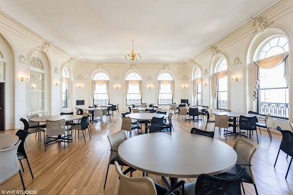 A large room with tables and chairs and arched windows at Mohican Apartments, New London, 06320