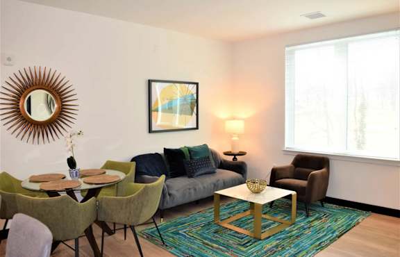 A grey couch with a pillow and a small table with a plant and a picture frame.