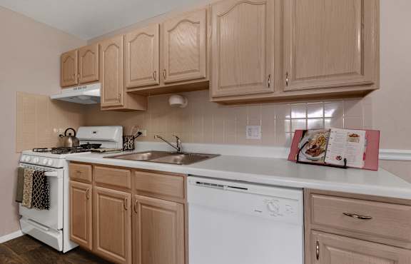 a kitchen with white appliances and wooden cabinets at St Charles Square Apartments, Carol Stream, IL, 60188