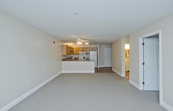 the living room and kitchen of an empty house with a ceiling fan