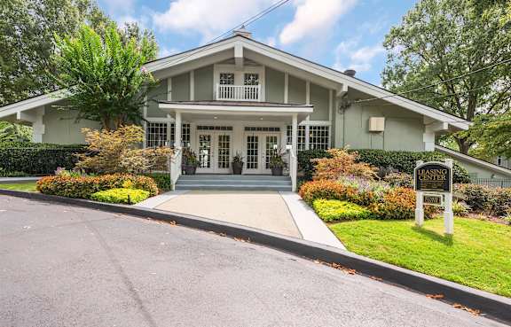A white house with a porch and a sign that says "GREEN".