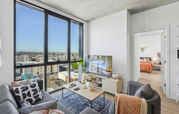 Living room with natural light and TV at Velaris Living Apartments, Denver, CO, 80205