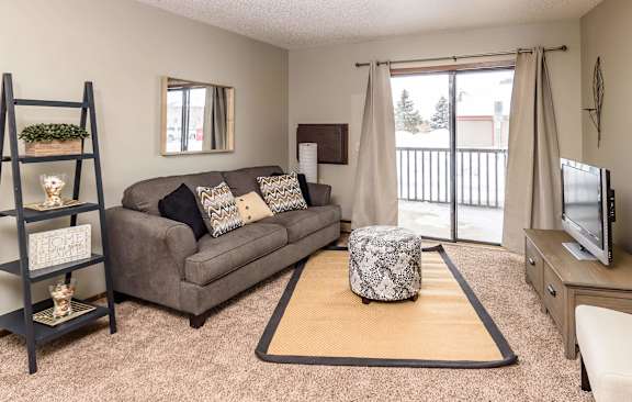 A living room with a grey couch and a brown rug.at Autumn Park, Sioux Falls South Dakota