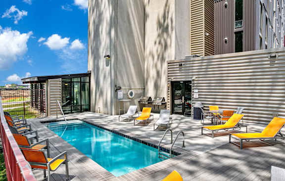 a swimming pool in the middle of a building with yellow chairs at City Square Lofts, Des Moines Iowa
