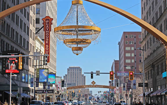 A street view of a busy intersection with a large hanging light fixture.