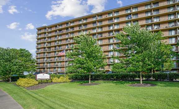 A large apartment building with a lawn in front and a sign that says at Independence Place Apartments, Parma Heights