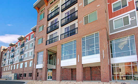 The red brick exterior with large windows and balconies at the Ritz Classic Apartment Homes. 