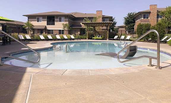 a swimming pool with chairs around it and a building in the ba at North Pointe Villas Apartments, Illinois, 68521
