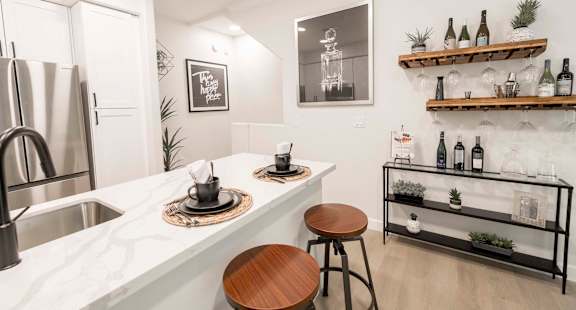A kitchen with a white marble countertop and a wooden stool.