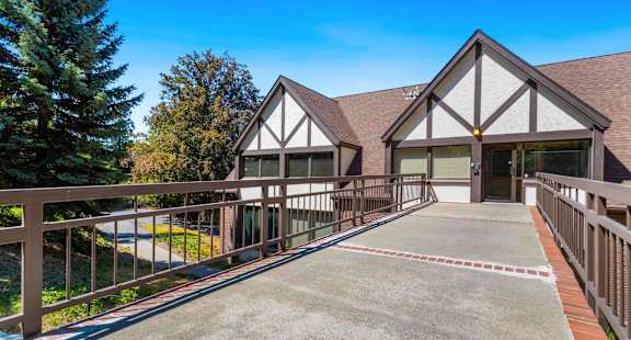 A house with a brown roof and white walls has a driveway leading to the front door.