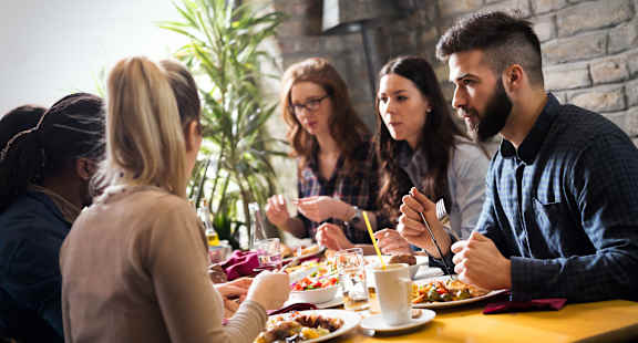 A group of people are sitting around a table eating food at Lenox Village Apartments, Atlanta, Georgia