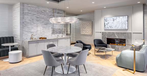 A modern dining room with a glass table and grey chairs.