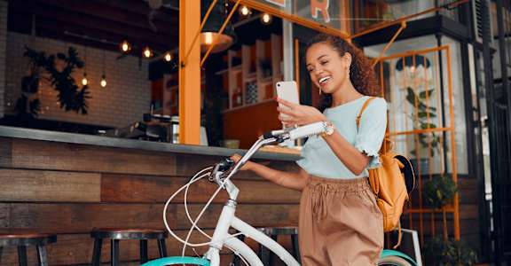 a woman standing next to a bike looking at her cell phone