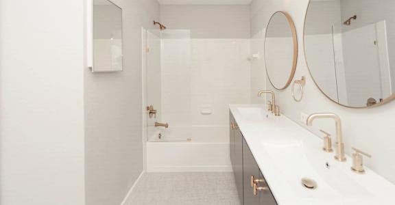 a white bathroom with a shower and a sink and a mirror at Ardenwood Apartments, North Haven, 06473