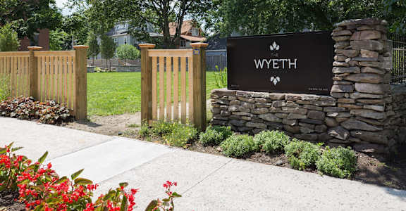 A sign that says Wyeth stands in front of a stone wall.