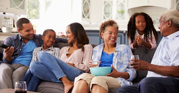 A group of people are sitting on a couch, enjoying a meal and drinks together.at Northside Hills Apartments, Griffin, 30223
