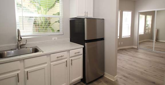 a kitchen with white cabinets and a stainless steel refrigerator