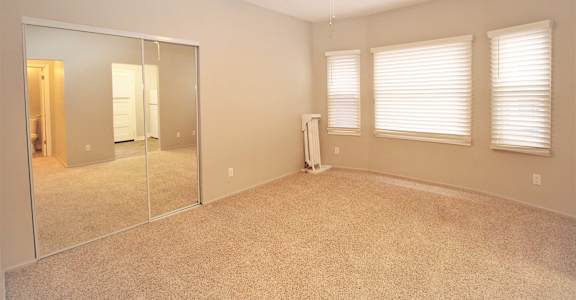 an empty bedroom with a ceiling fan and a mirror