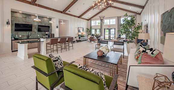 A modern living room with a stone fireplace and a large green sofa at Waterleaf at Neely Ferry Apartments, Simpsonville, SC 29680
