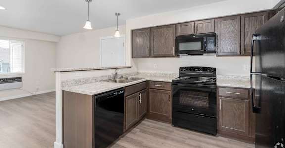 A kitchen with black appliances and wooden cabinets.