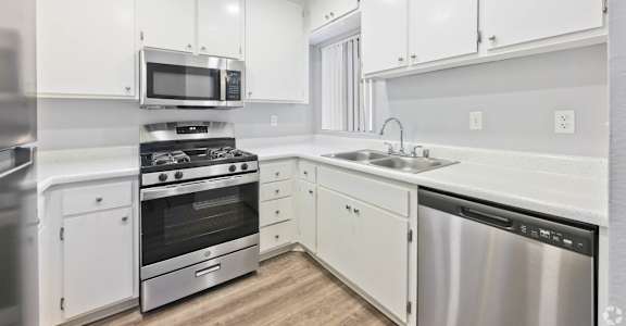 A modern kitchen with white cabinets and stainless steel appliances.