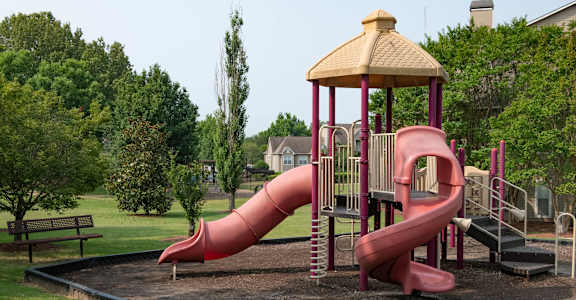 A playground with a red slide and a yellow roofed structure.