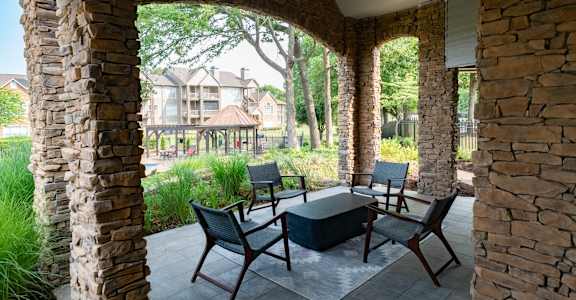 A patio with a table and chairs is framed by two stone pillars.