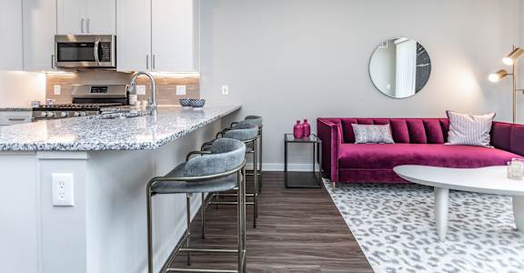 A modern kitchen with a pink couch and a marble countertop.