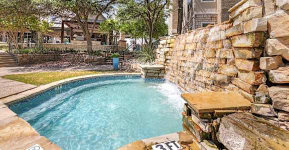 A stone wall surrounds a small pool.