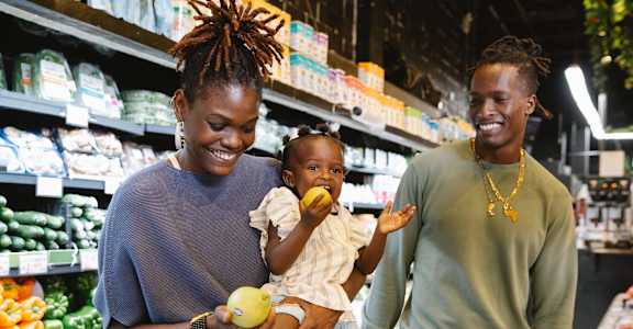A woman and a man are shopping with a child in a grocery store.