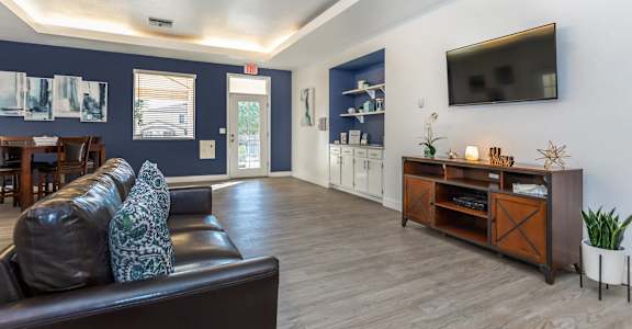 A living room with a brown leather couch and a wooden entertainment center.