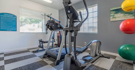 A gym with a treadmill, exercise ball and other equipment.