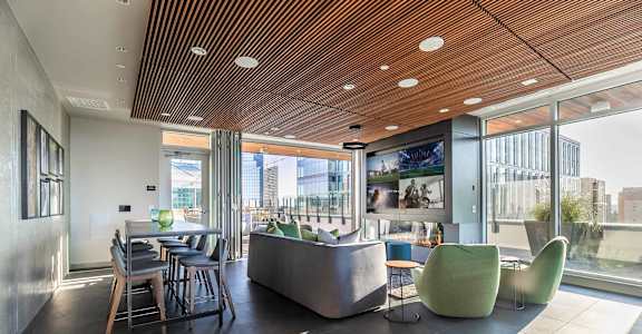 A modern interior space with a wooden ceiling and a large window overlooking a cityscape.