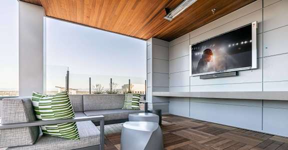A modern living room with a grey sofa and a television on the wall.